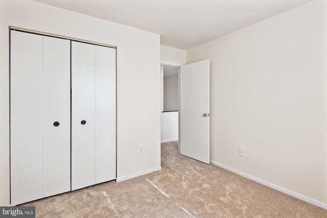 unfurnished bedroom with light colored carpet and a closet