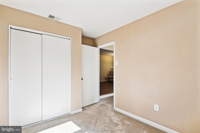 unfurnished bedroom with light colored carpet and a closet