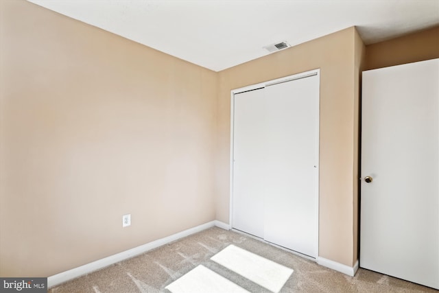 unfurnished bedroom featuring light colored carpet and a closet