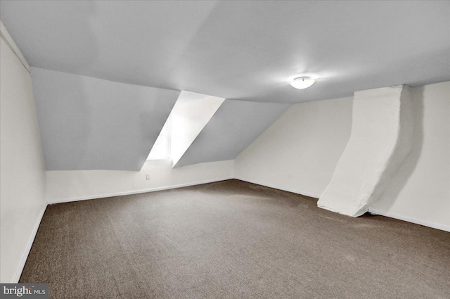 additional living space with vaulted ceiling, dark carpet, and baseboards