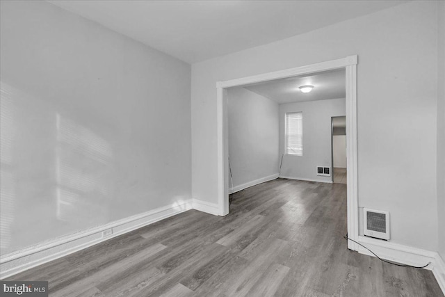 unfurnished room featuring baseboards, visible vents, and wood finished floors