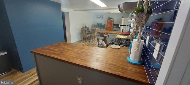 kitchen featuring stainless steel appliances, butcher block counters, and light hardwood / wood-style floors