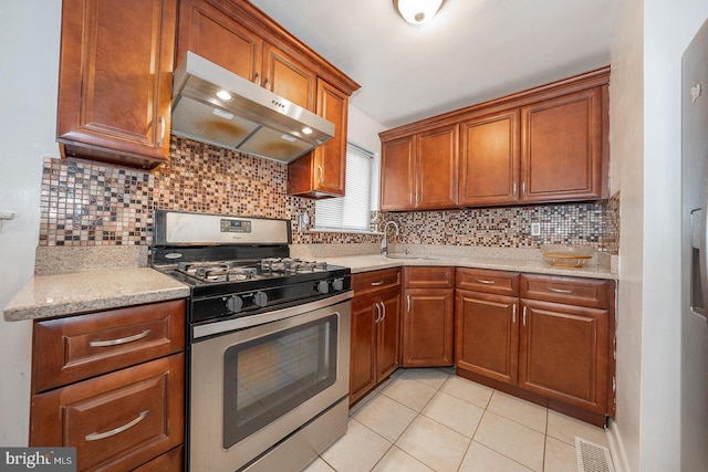 kitchen featuring tasteful backsplash, sink, light tile patterned floors, light stone counters, and gas stove