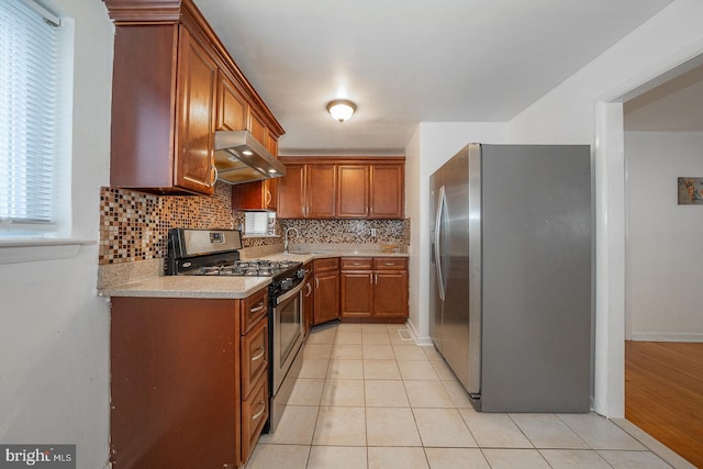 kitchen with light tile patterned floors, decorative backsplash, and stainless steel appliances