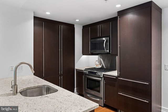 kitchen featuring dark brown cabinetry, appliances with stainless steel finishes, sink, and light stone counters