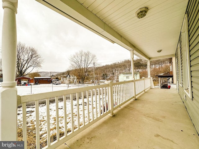 snow covered back of property with covered porch