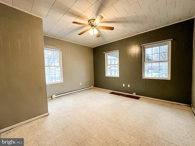 empty room with crown molding, a wealth of natural light, a baseboard radiator, and ceiling fan