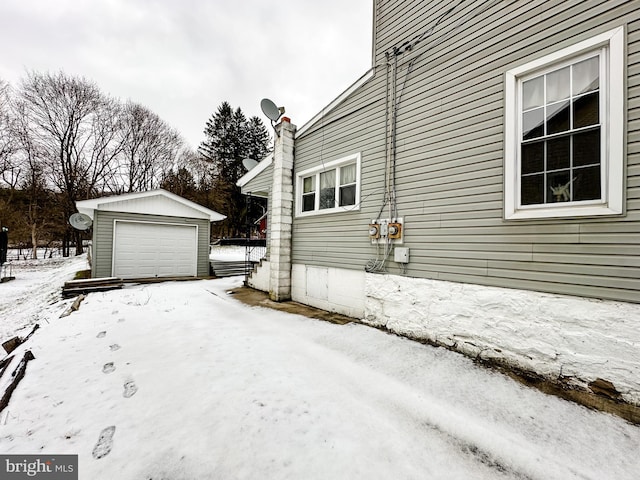 view of snow covered exterior with a garage and an outdoor structure