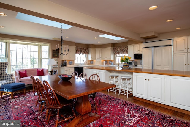 dining space featuring dark hardwood / wood-style flooring, sink, and a skylight