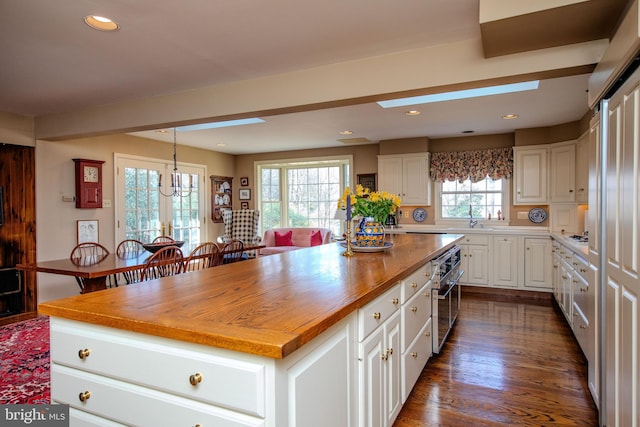 kitchen with oven, a center island, hanging light fixtures, and white cabinets