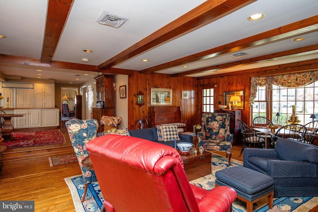 living room with beam ceiling, wooden walls, and light hardwood / wood-style floors