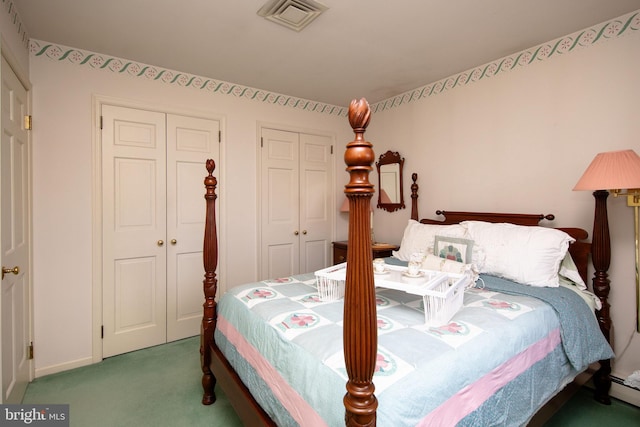 carpeted bedroom with two closets and baseboard heating