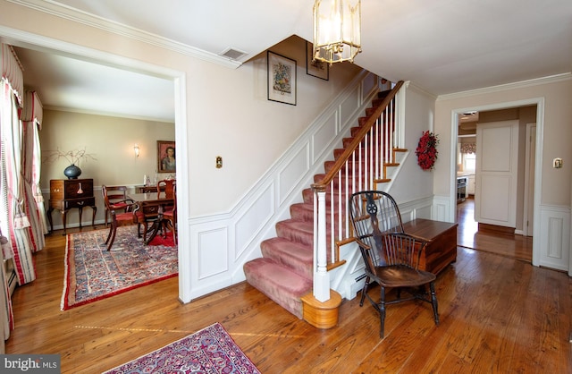 stairs with hardwood / wood-style flooring, ornamental molding, and a chandelier