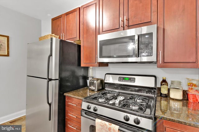 kitchen with stainless steel appliances and dark stone counters