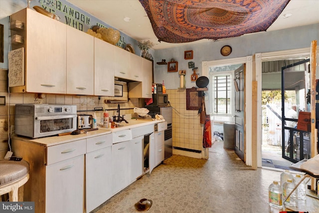 kitchen with white cabinetry and tile walls