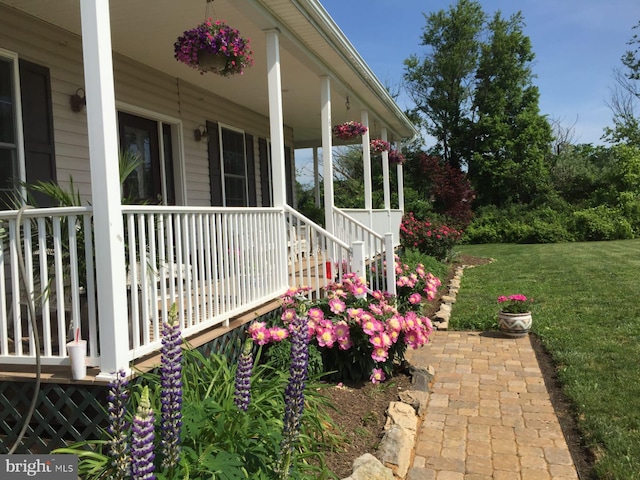 view of side of property featuring covered porch and a yard