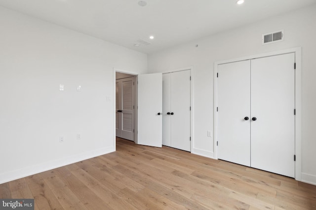 unfurnished bedroom with two closets and light wood-type flooring