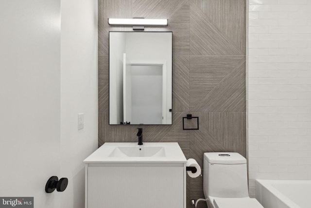 bathroom with vanity, tile walls, and toilet