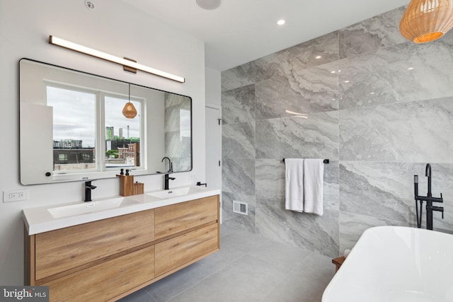 bathroom featuring a tub to relax in, vanity, and tile walls