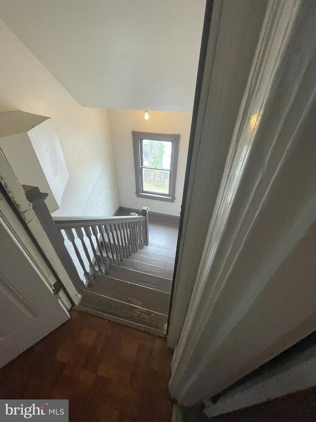 stairway with wood-type flooring and lofted ceiling