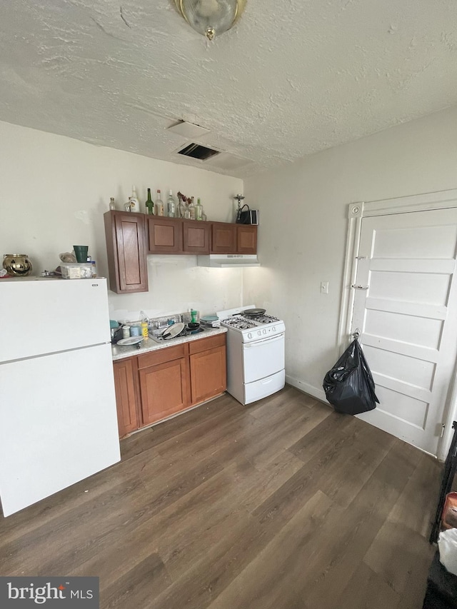 kitchen with white appliances, dark hardwood / wood-style flooring, and a textured ceiling