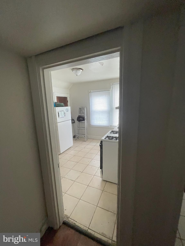 hallway with washer / clothes dryer and light tile patterned floors