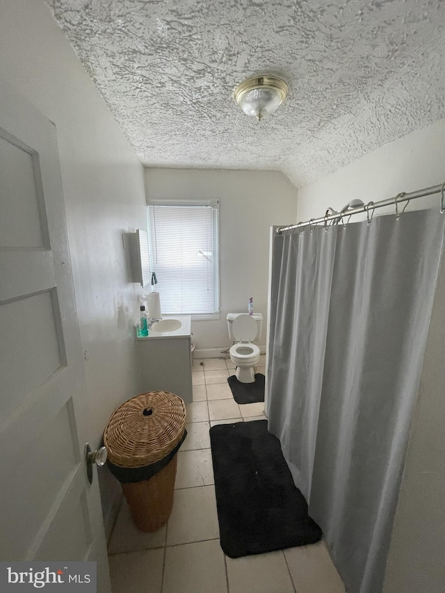 bathroom featuring lofted ceiling, tile patterned flooring, vanity, toilet, and a textured ceiling