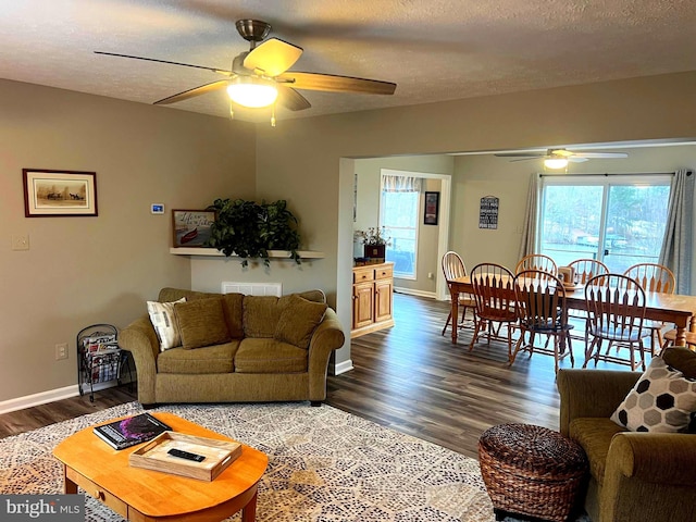 living room featuring ceiling fan, dark wood-type flooring, and a textured ceiling