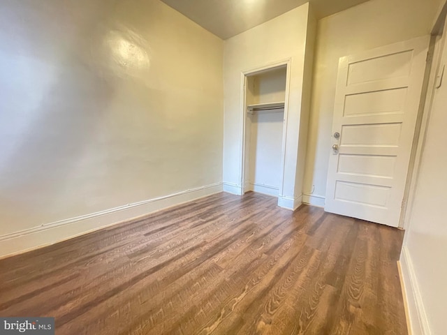 unfurnished bedroom featuring dark wood-type flooring and a closet