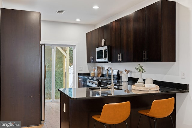 kitchen featuring a breakfast bar, kitchen peninsula, and appliances with stainless steel finishes