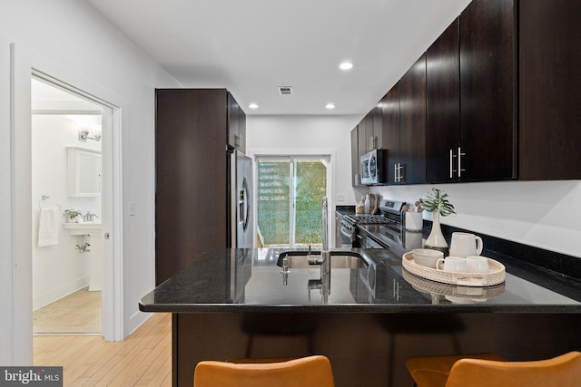 kitchen featuring appliances with stainless steel finishes, kitchen peninsula, sink, and dark stone counters