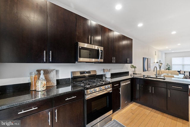 kitchen featuring appliances with stainless steel finishes, sink, dark brown cabinets, and light wood-type flooring