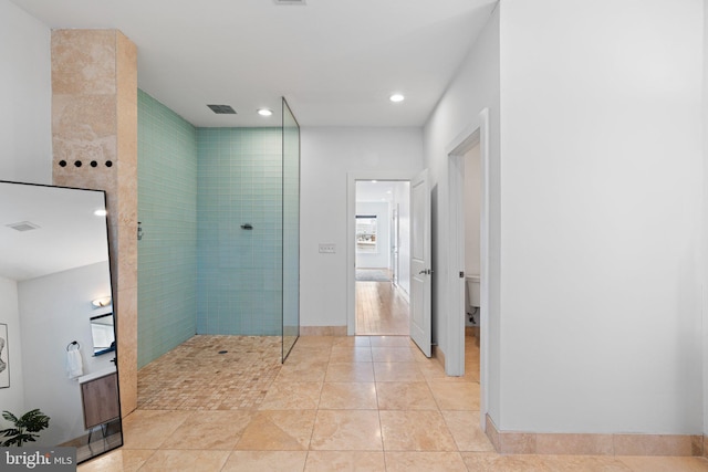 bathroom with a tile shower, tile patterned floors, and toilet