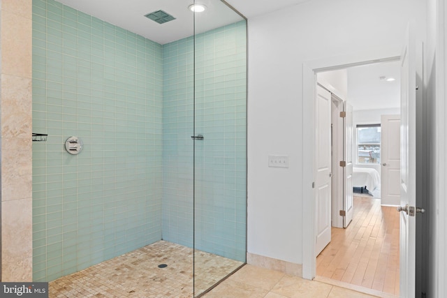 bathroom with tiled shower and tile patterned flooring