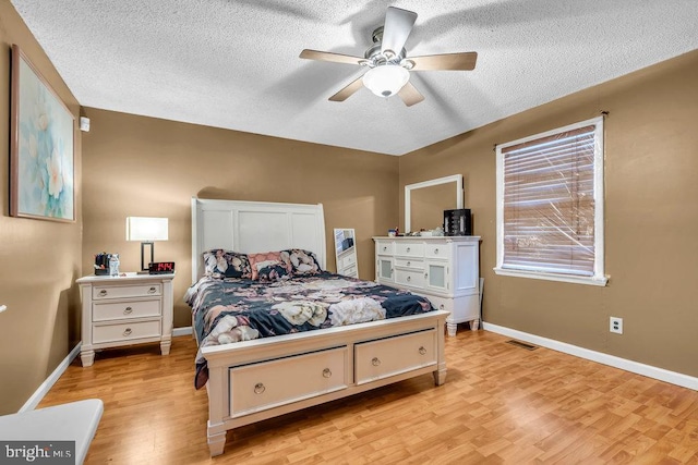 bedroom with light wood-type flooring, ceiling fan, and a textured ceiling