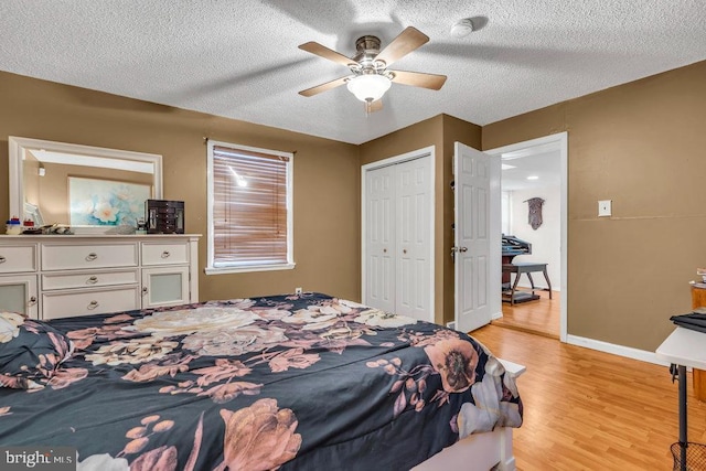 bedroom with ceiling fan, light hardwood / wood-style floors, a textured ceiling, and a closet