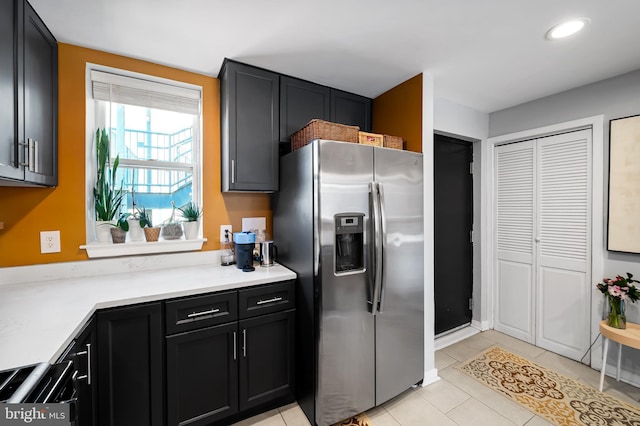 kitchen with stainless steel fridge, dark cabinets, light tile patterned flooring, light countertops, and recessed lighting