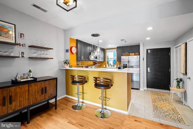 kitchen with visible vents, a kitchen breakfast bar, a peninsula, stainless steel appliances, and light countertops