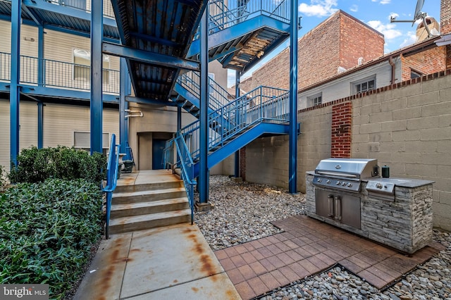 view of patio with stairway and a grill