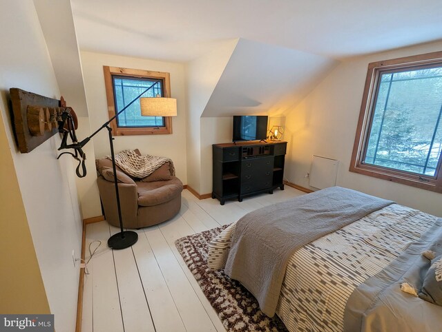 bedroom with lofted ceiling and light wood-type flooring