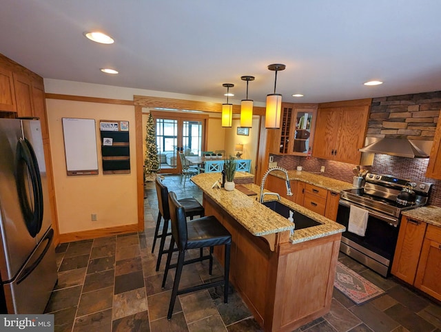 kitchen featuring a breakfast bar, sink, an island with sink, pendant lighting, and stainless steel appliances