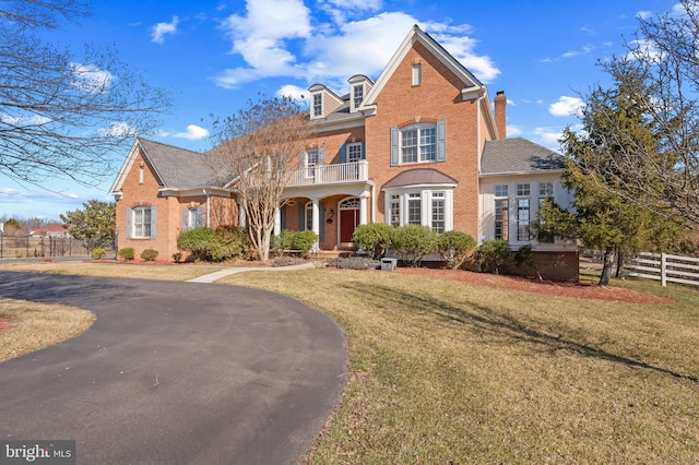 view of front facade with a front yard, brick siding, and fence