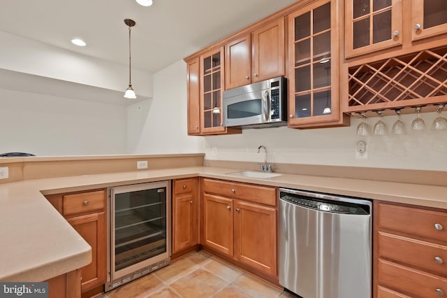 kitchen with beverage cooler, hanging light fixtures, stainless steel appliances, light countertops, and a sink