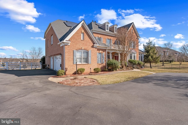 view of front of house with a garage, driveway, roof mounted solar panels, and fence