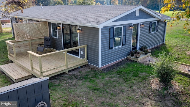 back of property with a wooden deck and a lawn