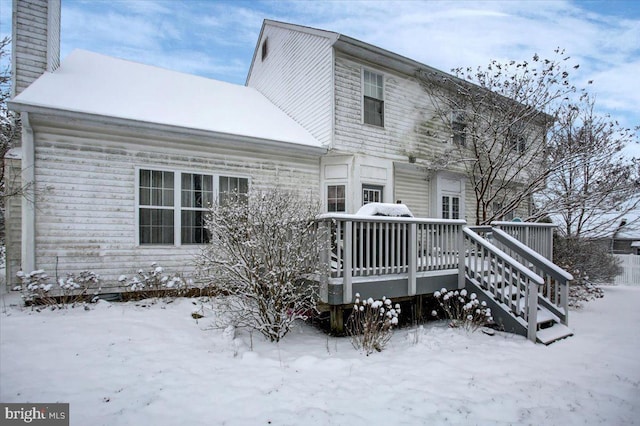 snow covered rear of property with a deck