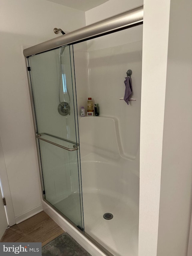 bathroom with an enclosed shower and hardwood / wood-style flooring