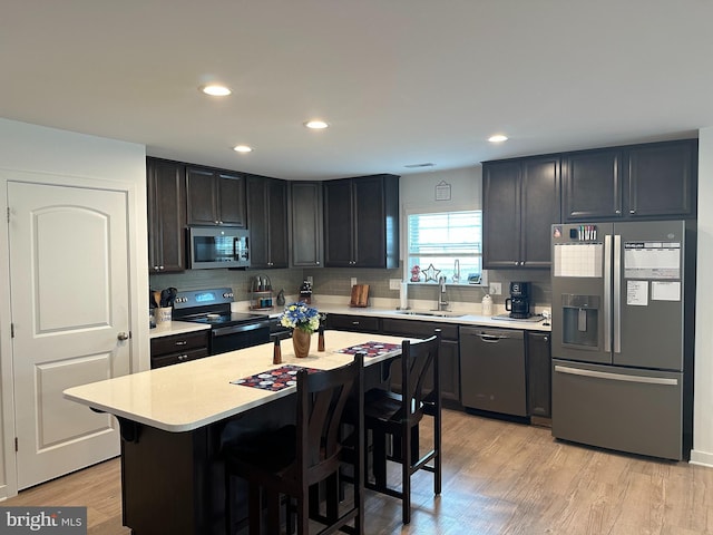 kitchen featuring sink, a breakfast bar area, a center island, light hardwood / wood-style floors, and stainless steel appliances