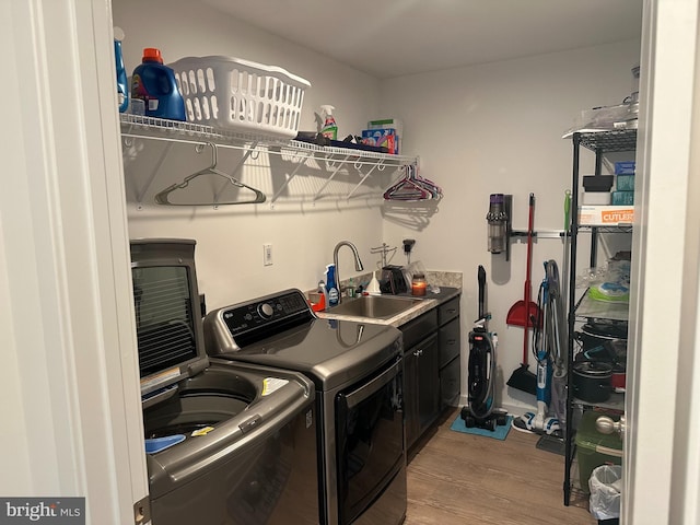 laundry area featuring cabinets, washer and clothes dryer, sink, and light hardwood / wood-style flooring