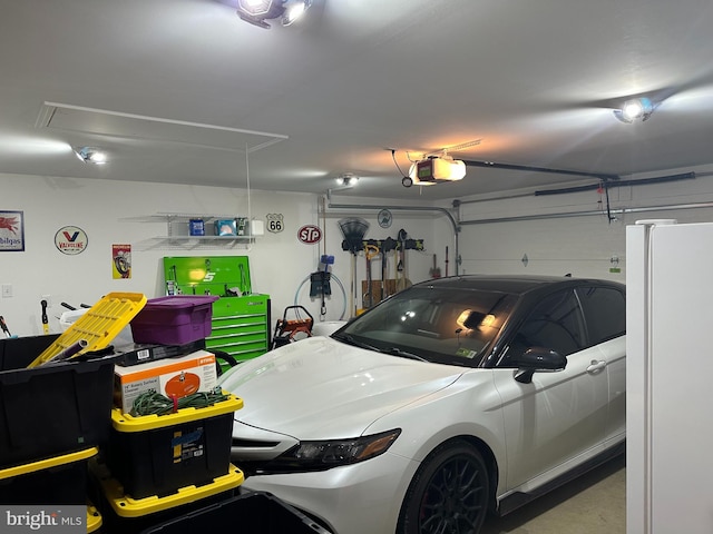 garage with a garage door opener and white refrigerator